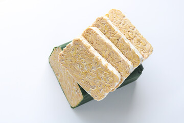 Fresh cut and closeup of Indonesian tempeh (tempe) wrapped in banana leaf and sliced into thick cuts. A traditional plant-based protein made from fermented soybeans.