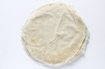 Top view of a stack of thin spring roll wrappers or skin, displayed against a clean white background. These delicate and versatile sheets are a staple in Asian cuisine.