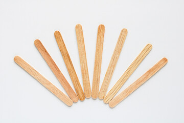 A collection of natural wooden craft sticks or popsicle sticks, fanned out neatly in an arc on a clean white background, ready for various projects.