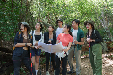 Group of young hikers checking map in dense forest