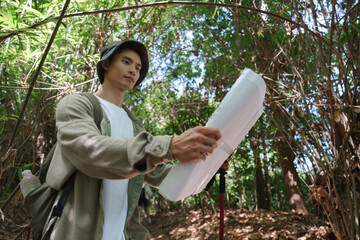 Young man navigating forest path with map
