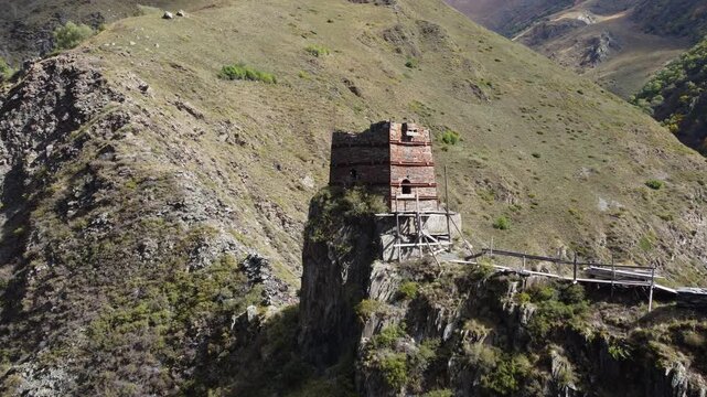 Amazing drone fly to the ancient half fortified stone tower standing on rocky cliff on Mutso village mountain environment, Khevsureti, Mtskheta-Mtianeti, Georgia.