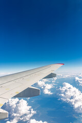 Fototapeta premium View from the airplane window at a beautiful cloudy sky and the airplane wing