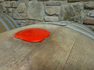 Close-up of a wooden wine barrel sealed with red wax in a traditional stone wine cellar