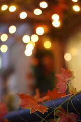 Warm golden bokeh lights create a cozy autumn atmosphere, complemented by vibrant red maple leaves...