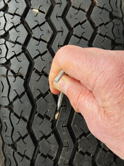 Closeup of a man’s hand using a hex or allen key to prise and remove a small stone from the tread...