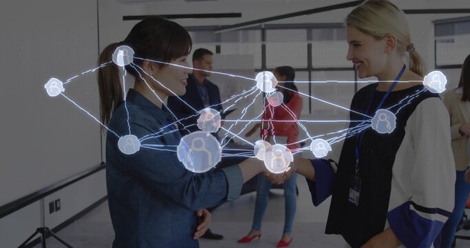 Exchanging handshake between two businesswomen in conference room with digital network overlay