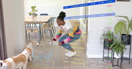 Crouching woman offering metal bowl toward two dogs in home dining area, with stock market overlay