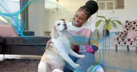 Kneeling woman wearing pastel sweater, petting white and tan dog on shag rug in living room