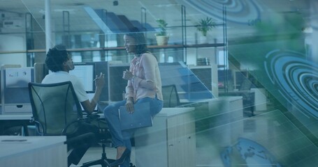 Discussing project man and woman wearing business casual in office, with AR schematics on monitors