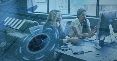 Collaborating mature businesswomen analyzing data in office, with digital interface and notebooks