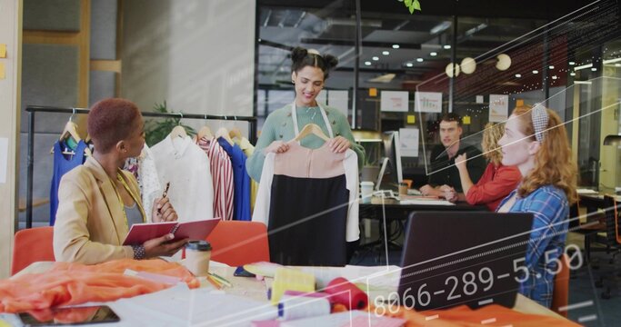 Presenting woman holding color-blocked dress at fashion studio, with fabric rolls and wooden hanger
