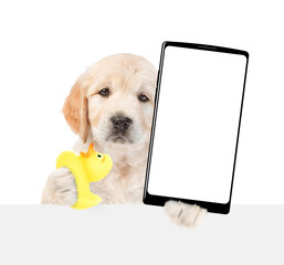 Golden retriever puppy holds rubber duck and big smartphone with white blank screen in it paw above blank white banner. isolated on white background