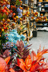 Artificial autumn leaves, berries, and blue florals in a styled home retail display. Seasonal transitions, faux botanicals, retail styling, sustainable decor