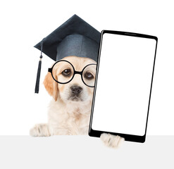 Smart college graduate Golden retriever puppy holds big smartphone with white blank screen in it paw, showing above empty white banner. isolated on white background