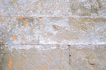 Close-up of weathered stone wall with mineral deposits and lichen growth, showcasing rough texture and aged patina