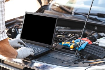 Mechanic uses a laptop to record error engine checks