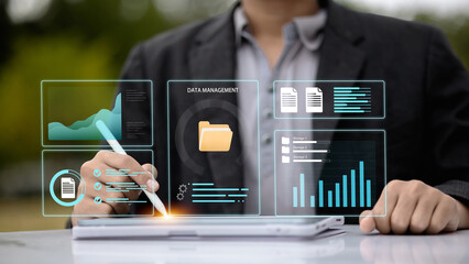 Businessman using stylus on digital tablet with virtual data management dashboard and analytics interface