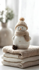 Obraz premium Cozy winter still life with a cute ceramic snowman and knitted textiles