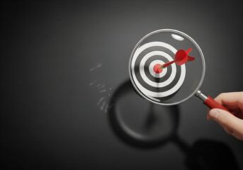 Target symbol under magnifying glass on black background, concept of goal focus, precision, marketing strategy, business success, achievement
