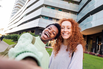 selfie of two young women in front of a building, concept of friendship and youth lifestyle, copyspace for text