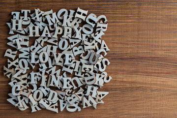 Pile of wooden letters of the English alphabet, laid out in a chaotic order on a table, closeup, top view, copy space. Background of many wooden letters