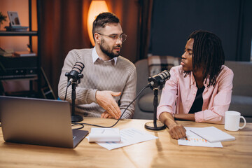 Two young male podcasters are discussing and recording a new episode in a professional studio