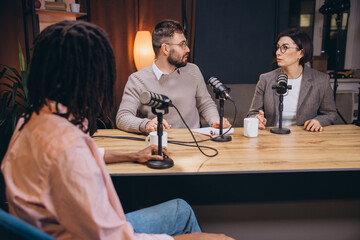 Diverse team of radio hosts engaging in lively discussions during a dynamic live podcast recording in a modern studio environment