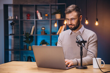 Podcaster working on laptop with professional microphone, capturing audio content in home recording space with digital creativity