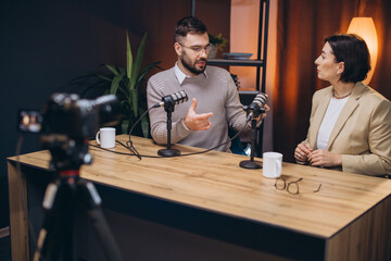 Content creators recording a podcast episode using professional microphones and a camera in a modern studio