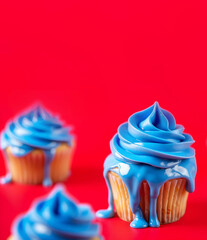 Vibrant Blue Icing Cupcakes on a Bold Red Background with Shallow Depth of Field