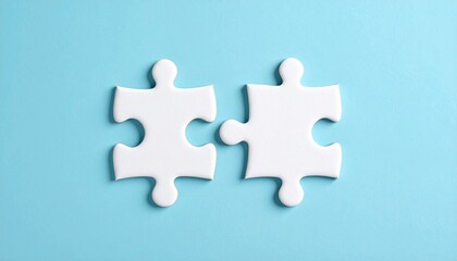 Obraz premium two white puzzle pieces matching together againt light blue background 