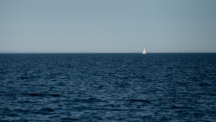 Sailing across calm waters on a clear sunny day near an expansive horizon