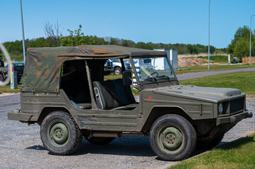 Military utility vehicle parked near recreational area on a sunny day