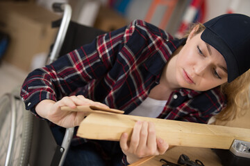 young lady in wheelchair preparing wood with sandpaper