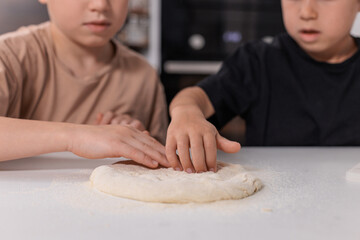 Two boys sitting at a kitchen table preparing ingredients, concept of home cooking, learning through play and developing love for culinary activities.
