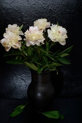 Still life- peony flowers in a clay vase on a dark background