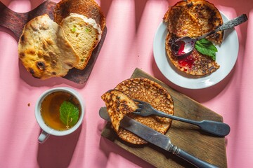 Still life - blueberry jam, green tea and pancakes. Food and drink on a pink background