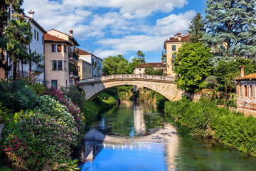 Picturesque Ponte San Michele bridge over the Baciglione River in Vicenza surrounded by lush greenery and charming buildings. Vicenza, Veneto region of Italy