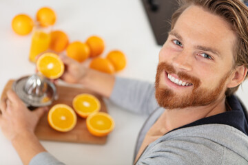 young man making orange fresh on kitchen