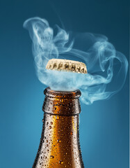 Opening chilled beer bottle on blue background. Gas impurring from the beer bottle and blows cap off.