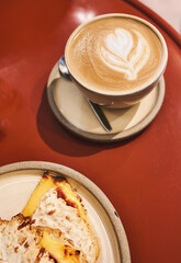 Coffee with Latte Art and Grilled Sandwich (Tostado) on Red Table