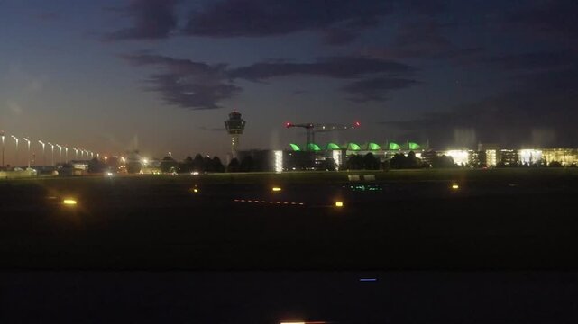 Airplane landing at Munich Airport in Germany at night, with runway lights glowing in the dark. Aviation and travel concept