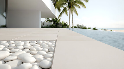 Seaside bliss: Modern architecture meets tropical serenity. Smooth, neutral tiles and white stones lead to an infinity pool overlooking the ocean with palm trees swaying.