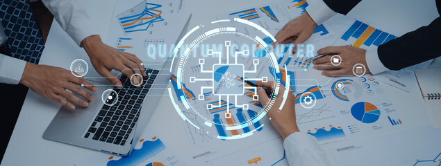 A group of professionals collaborates over charts and digital data on a table, using a laptop to enhance their analysis in a modern office setting. Trope