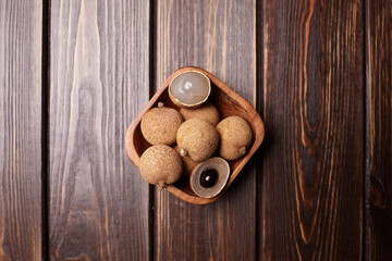 Longan tropical fruit displayed in a wooden bowl on a rustic wooden table, showcasing its unique texture and natural beauty, perfect for culinary and health concepts
