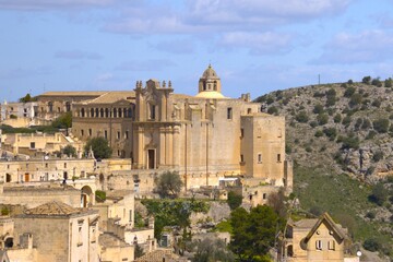 Obraz premium Sunlit Hilltop Church Above Ancient Stone Quarter, Italy, Matera