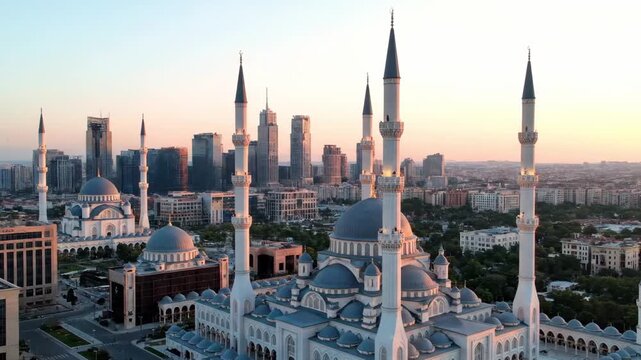 Aerial View of a Grand Mosque at Sunset with Modern City Skyline.