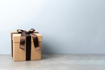 Elegant brown kraft gift box with ribbon bow on light background, minimalist holiday present packaging design, eco friendly wrapping for birthday, Christmas, wedding, anniversary,  special occasion
