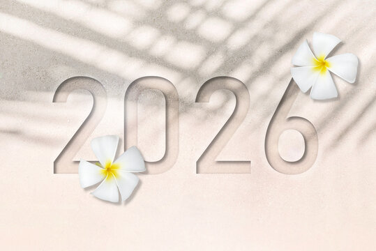 Happy New Year 2026 greeting card, Flat lay or top view of number 2026 debossing on white sand beach texture with shadows of palm leaf and white Plumeria flowers. New Years concept.